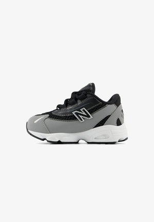 Zwarte en grijze New Balance sneaker met witte zool, mesh panelen en gestikte "N" logo aan de zijkant, weergegeven vanaf de buitenzijde.