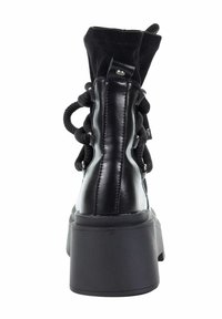 Czarne buty z wysokim, teksturowanym kołnierzem z tkaniny, masywną czarną platformą oraz dekoracyjnym wiązaniem. Widoczne gładkie skórzane detale.