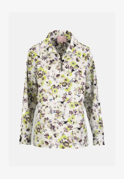 Blouse blanche à manches longues avec imprimé floral vert, marron et violet, col boutonné et deux poches plaquées avant.
