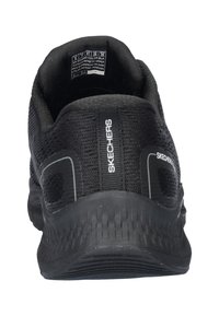 Zapato deportivo negro de Skechers visto desde atrás, con un upper texturizado, cuello acolchado y logo en el lateral.