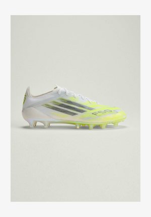 Weißer und neon-gelber Fußballschuh mit schwarzen Streifen und geformten Nocken auf einem schlichten hellen Hintergrund, seitlich betrachtet.