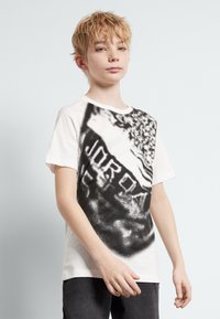 White T-shirt featuring a black graphic print, including the word "JORDAN," with short sleeves and a round neckline.