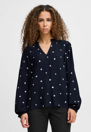 Marinebluse mit V-Ausschnitt, langen Puffärmeln und weißen Herzmustern. Das weiche Gewebe sorgt für eine glatte Textur.