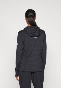 Black striped hoodie with a hood, featuring a logo on the back, made from a textured fabric with long sleeves and fitted design.