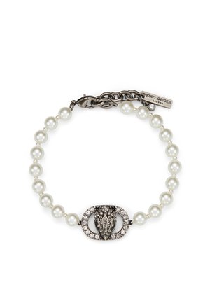 Bracelet avec un rang de perles blanches, un fermoir ovale central en argent orné de cristaux, et une étiquette en métal gravée « Kurt Geiger London ».
