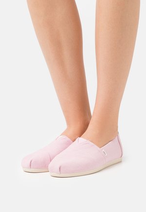 Helle rosa Slipper aus strukturiertem Stoff mit flacher Sohle, runder Zehenpartie und einem kleinen, seitlich eingestickten Logo.