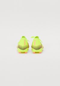 Neon yellow soccer cleats with striped accents, textured upper, and pink-tipped studs, featuring a secure lace closure and branding detail.