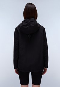 Giacca nera con cappuccio, realizzata in materiale leggero. Dotata di un orlo regolabile, maniche lunghe e una cinghia sul retro per la regolazione.