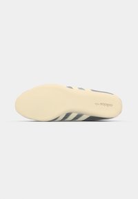 Adidas sko såle i kremgummi med tre blå striper og teksturert mønster. Merkevarelogo trykket på siden. Flat, avrundet form.