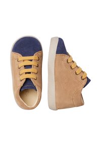 Baskets en suède beige avec un capuchon de orteil bleu marine, des lacets jaunes et une semelle en caoutchouc blanche. Forme arrondie avec une texture douce.