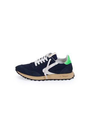 Scarpa da ginnastica blu navy con lacci bianchi, suola beige, logo laterale bianco e linguetta posteriore verde brillante, mostrata di profilo su sfondo bianco.