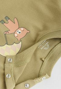Alyvuogių žalumo bodysuit su piešiniu, vaizduojančiu mešką, laikantį skėtį. Savybės: spaudimo mygtukai apačioje ir minkšta medvilnės tekstūra.