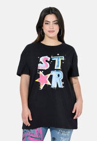 Camiseta de algodón negra con un colorido gráfico de "STAR" que presenta estrellas y un diseño salpicado. Mangas cortas y un corte relajado.