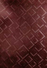 Țesătură burgundy cu un model geometric embossat, prezentând pătrate și dreptunghiuri interconectate, creând o suprafață texturată.