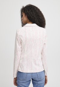 Witte blazer met roze en groene verticale strepen, lange mouwen en met een gekartelde kraag. Geverfde stof en een getailleerde pasvorm.