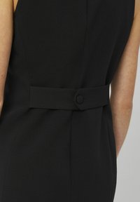 Robe noire avec une silhouette ajustée, un tissu texturé, une couture au dos et un détail de ceinture boutonnée pour un look soigné.