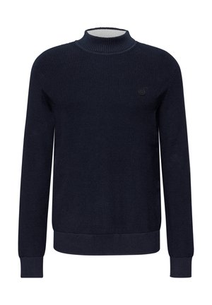 Pull en tricot côtelé bleu marine avec un col montant, des manches longues et un petit logo sombre sur la poitrine gauche.
