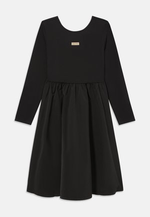 Must hõlmik, millel on pehmest materjalist sobituv pikkade varrukatega pluus ja kulgeva lõikega seelik, millel on kokku kogumise detail. Rinnas Calvin Kleini logo patsch.