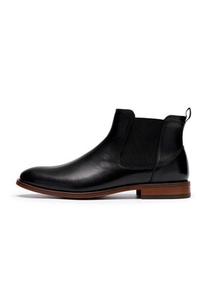 Black leather Chelsea boot with elastic side panel, brown stacked heel, and pull tab at the back, shown in side profile on white background.