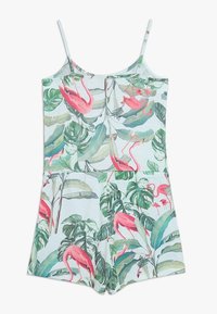 Blommig jumpsuit med tunna axelremmar, med en ljusblå bakgrund, rosa flamingoutskrifter och gröna tropiska löv. Mjuk, lättviktig tyg.