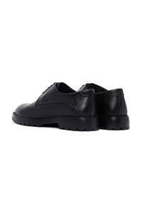Zwarte leren schoenen met een gladde afwerking, getextureerde accenten en een stevige rubberen zool met profielpatronen voor grip.