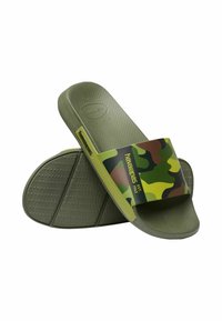Sandali di gomma verdi con una fascia a motivo mimetico. Il testo sulla fascia recita "havaianas EST. 1962." Suola texturizzata per una migliore aderenza.
