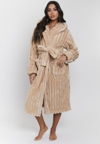 Accappatoio plush beige con colletto a scialle, cintura da legare e texture a coste. Presenta un orlo scallop e maniche lunghe per il comfort.