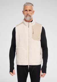 Fleece vest i creme med en tan accentpanel, fuld lynlås, to forlommer og en lynlåslomme på brystet. Tekstureret finish med et blødt udseende.
