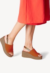 Braune Keilsandalen mit einer strukturierten Kork-ähnlichen Sohle, offenen Zehen und einem Slingback-Riemen. Glattes Obermaterial in einem kräftigen Orangeton.