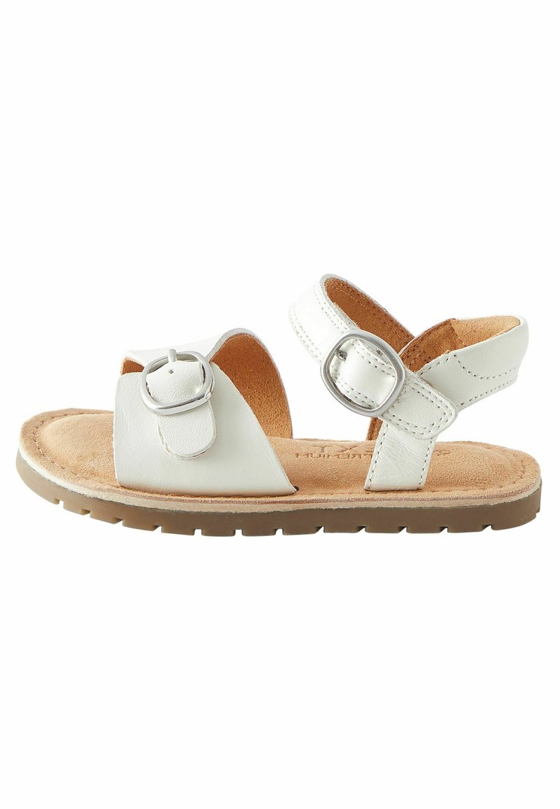 Bílé kožené sandály s nastavovacími přezkami, měkkou béžovou stélkou a texturovanou hnědou gumovou podrážkou. Design s otevřenou špičkou.