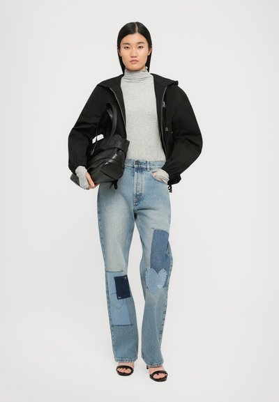 Črna bomber jakna, siva turtleneck majica in svetlo modri kavbojski jeans z denimskišnimi krpikami. Črna torba in črne sandale na peto.