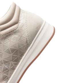 Beige sneaker heel with padded collar, metallic geometric pattern on suede upper, and white sole with brown rubber outsole.