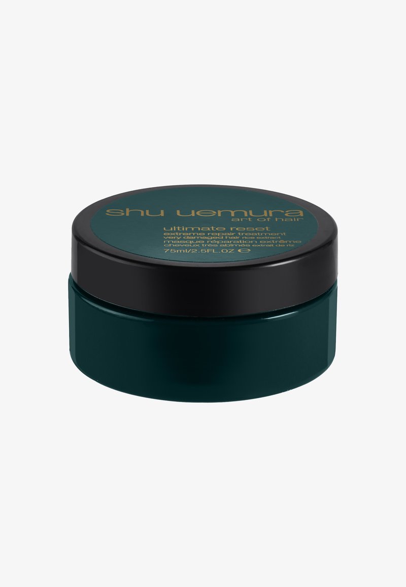 Donkergroene ronde container met zwart deksel gelabeld "Shu Uemura ultimate reset extreme repair hair treatment" in gouden tekst.
