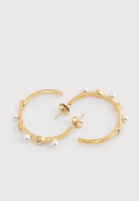 Guld hoop øreringe med små hvide perler og klare ædelsten jævnt fordelt langs hoops, præsenteret på en hvid baggrund.