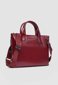 Rode leren tas met dubbele handvatten, een afneembare riem en blauwe accenten. Heeft een gestructureerde vorm en een hoofdvak met rits.