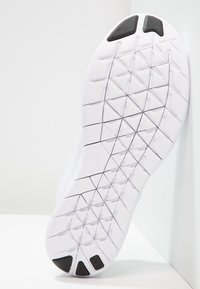 Suela de zapato deportivo blanco con un patrón de cuadrícula texturizado para tracción, con acentos negros cerca del talón para mayor agarre y durabilidad.