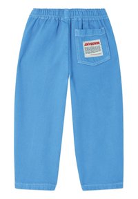 Pantalon bleu clair à taille élastique avec une poche arrière droite comportant une étiquette blanche avec un texte rouge et noir indiquant "AMVDENIM."