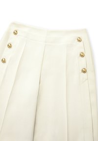 Cream-colored trousers featuring pleats and decorative gold buttons along the side, with a smooth texture and tailored fit.