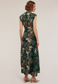 Rochie florală lungă, verde, cu mâneci scurte. Prezintă o talie ajustată, fustă fluidă și modele florale în nuanțe de roz și brun. Textură netedă.