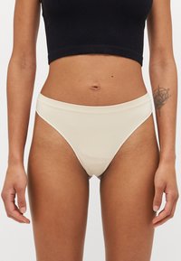 Crèmegekleurde ribbel hoge taille slip met een gladde, elastische tailleband en minimale bedekking, voorzien van een zachte textuur en geen zichtbare naden.
