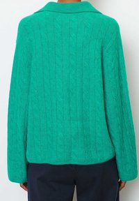 Green cable-knit cardigan with a collar, featuring long sleeves and a textured pattern on the back. Soft, loose-fitting design.