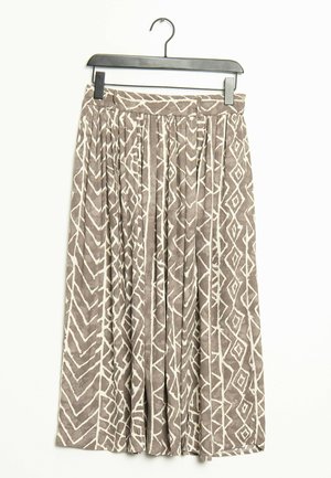 Beige midinederdel med hvide geometriske zigzag- og diamantmønstre, plisseret stof, hængende på en sort bøjle mod en hvid baggrund.