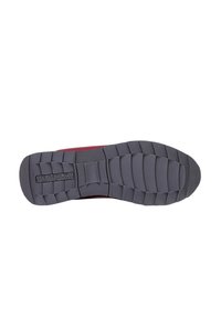 Suola di scarpa in gomma con un motivo testurizzato, caratterizzata da scanalature verticali per una migliore aderenza e un logo ben visibile. Colore principalmente grigio scuro con accenti.