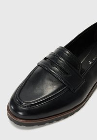 Mocassino in pelle nera con una finitura liscia, caratterizzato da una fascia rialzata sopra il collo del piede e una suola in gomma marrone per una migliore presa.