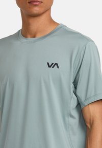 Camiseta deportiva de color azul claro, hecha de un tejido transpirable, con un cuello redondo y un pequeño logo negro en el lado izquierdo del pecho.