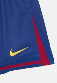 Modre Nike kratke hlače z rdečimi stranskimi črtami, s poudarjenim rumenim izvezenim logotipom. Narejene so iz gladkega, lahkega blaga z športnim krojem.