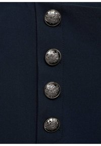 Quatre boutons argentés brillants avec des motifs embossés complexes, disposés verticalement sur un tissu bleu marine foncé.