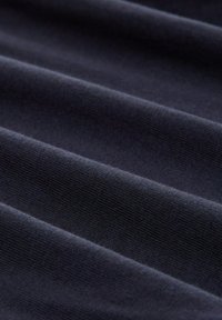 Marineblaue Stoff mit weicher Textur, der subtile Falten und eine glatte, einheitliche Oberfläche aufweist. Keine Muster oder Hardware sichtbar.