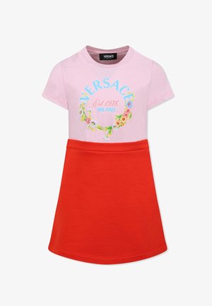 T-shirt rosa con stampa floreale e testo "VERSACE MILANO", abbinato a una gonna rossa brillante, progettato per un look giocoso e colorato.
