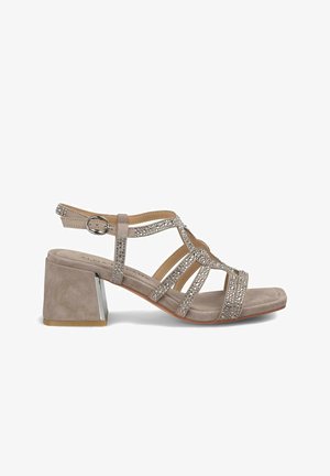 Sandales à talons en suede beige avec un talon carré, ornées d'accents en cristal décoratifs et de multiples brides croisées pour un maintien sécurisé.
